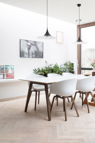 Design tafel met 6 witte stoelen en eetkamer en planten